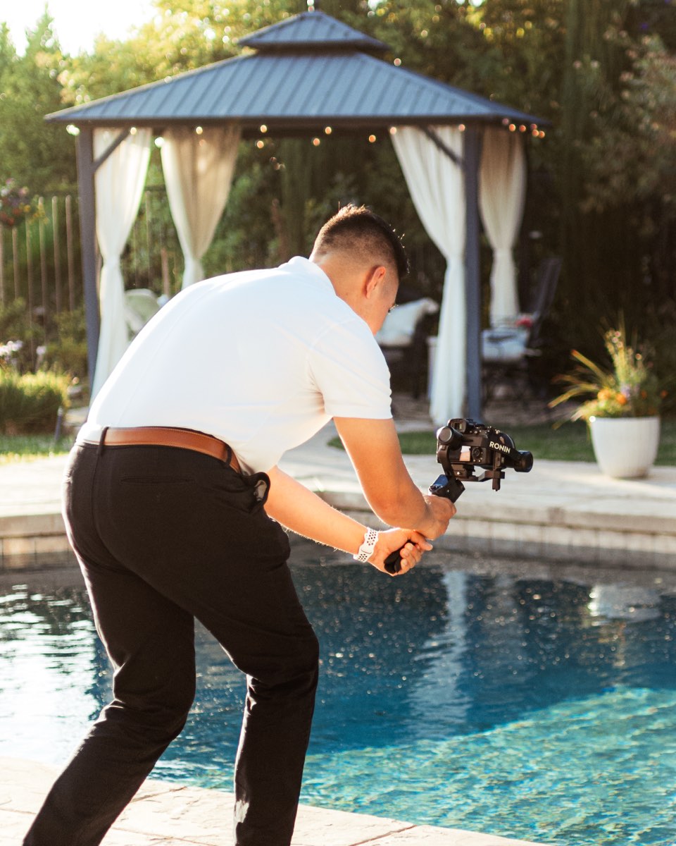 Videographer capturing a gimbal shot beside a backyard pool