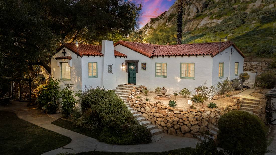 1920s Spanish bungalow at dusk beneath the rocks